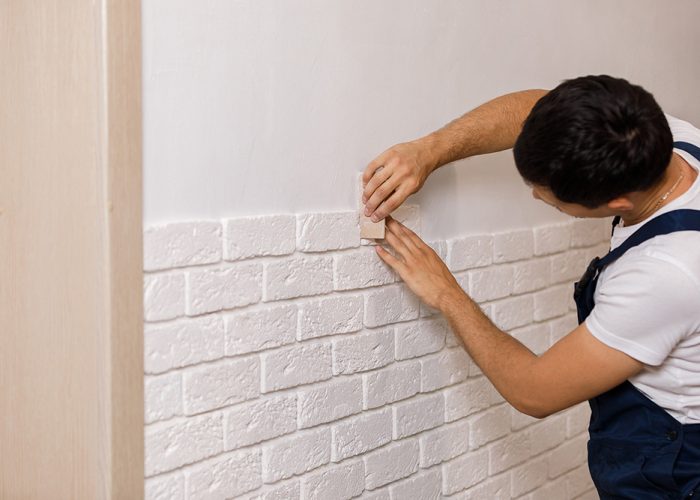 Professional Builder gluing decorative tile on wall. worker mounts decorative brick on wall